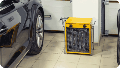 A stand-alone garage heater in a garage next to a black car