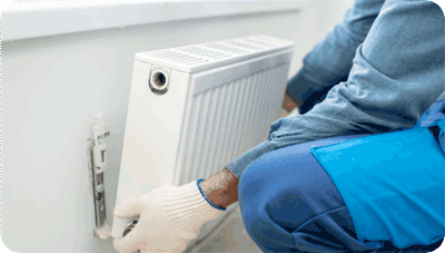 An HVAC tech removing a wall mounted radiator